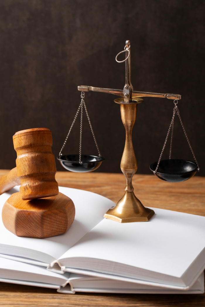 Balance de justice en laiton et marteau de juge posés sur un livre de droit